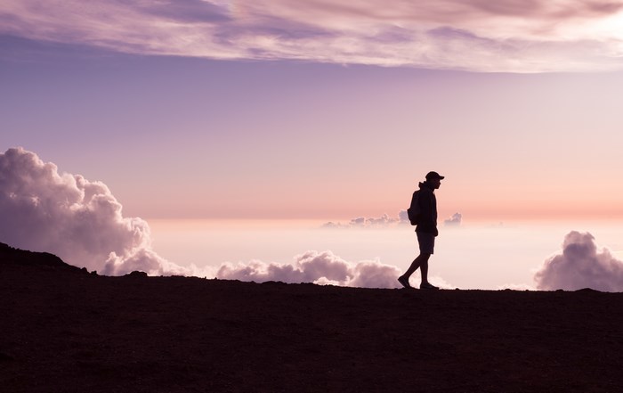 Silhouette of a man walking on a mountain at sunset