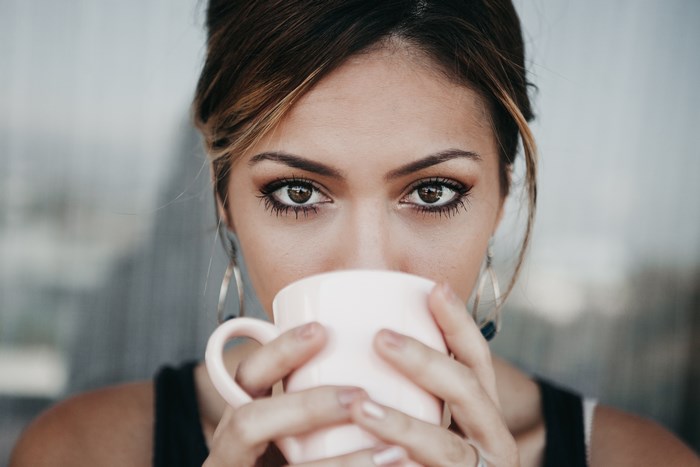 Woman drinking coffee with intense brown eyes