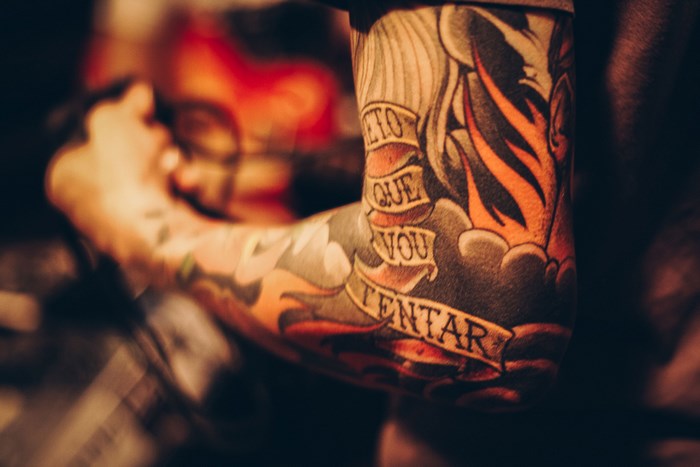 Man's arm with colorful tattoos and flames