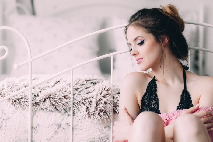 Woman in black lace lingerie sitting on a bed