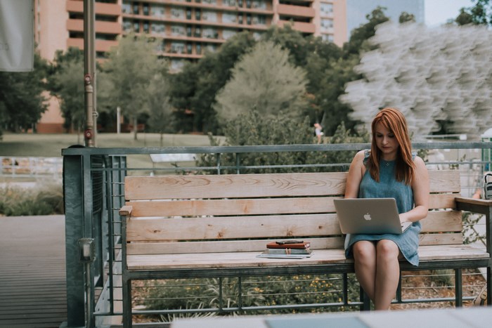 Woman working on a laptop on a bench