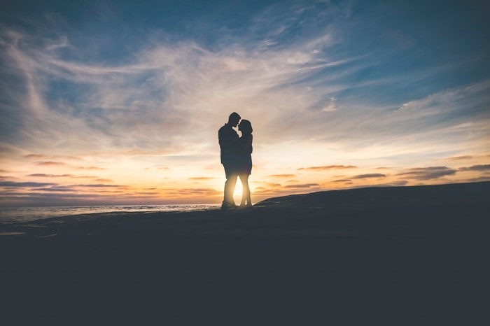 Couple silhouetted against a sunset sky