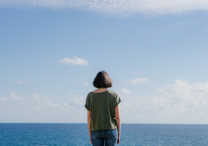 Woman in green shirt looking at the ocean