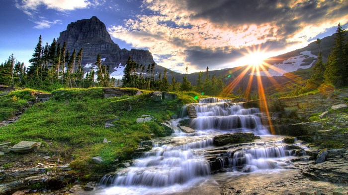 Mountain waterfall at sunset with sunburst
