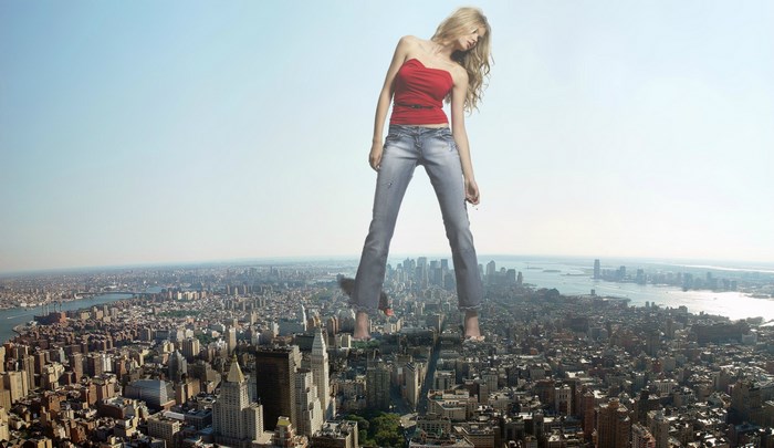 Giant woman in jeans and red top over city