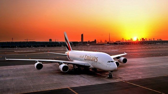 Emirates Airplane Taxiing at Sunset with City Skyline