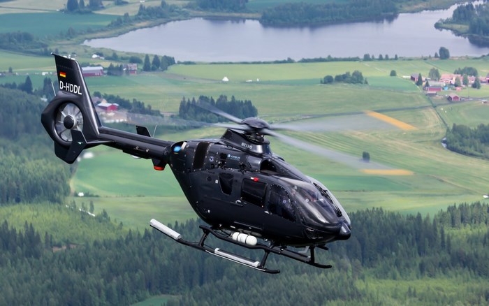 Black Eurocopter EC135 Helicopter Flying Over Rural Landscape