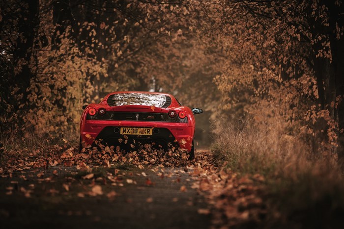 Red Ferrari F430 on a leaf-covered road