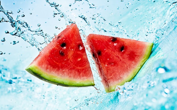 Two watermelon slices splashing in water