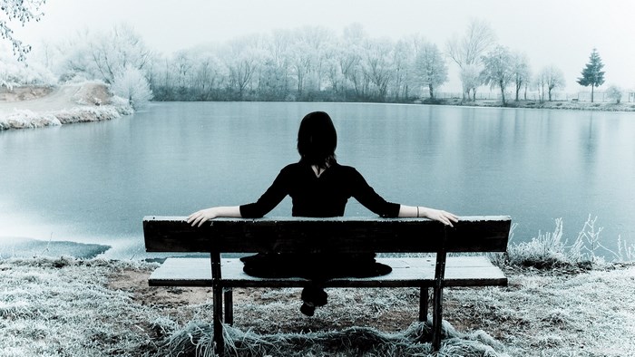 Woman sitting on a bench by a frozen lake