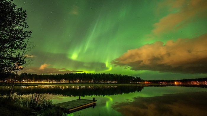 Aurora Borealis over a lake with a wooden dock