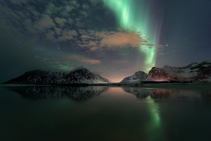 Aurora Borealis over snow-capped mountains and reflection