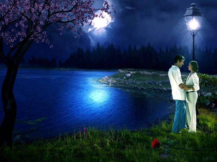 Couple under a lamp by a lake at night