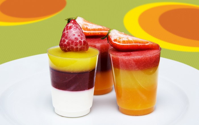 Layered fruit desserts with berries on a white plate