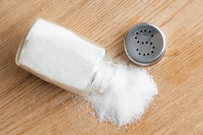 Salt shaker spilled on a wooden surface