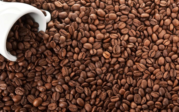 Coffee beans spilling from a white cup