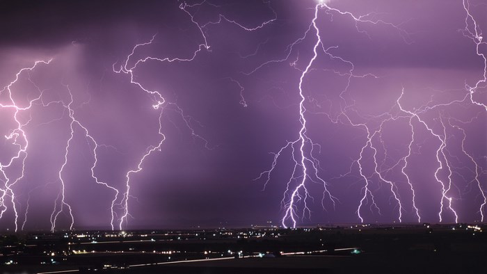 Multiple lightning strikes over a city at night