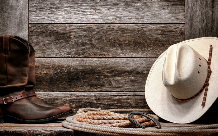 Cowboy boots, hat, rope, and horseshoe on wood