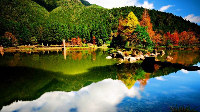 Autumn trees reflected in a calm lake with mountains