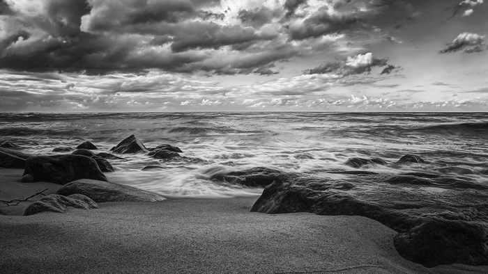 Ocean waves crashing on rocky shore under cloudy sky