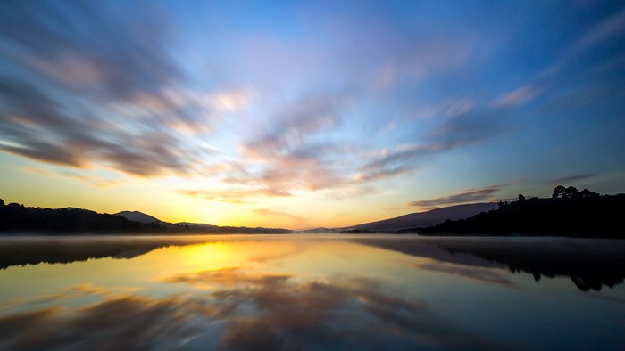 4K sunrise over a misty lake with clouds
