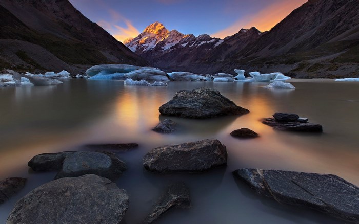 Mountaintop lake with icebergs and rocks at sunset