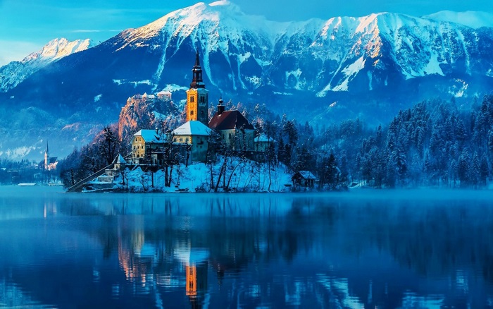Church on island in snowy mountains with lake