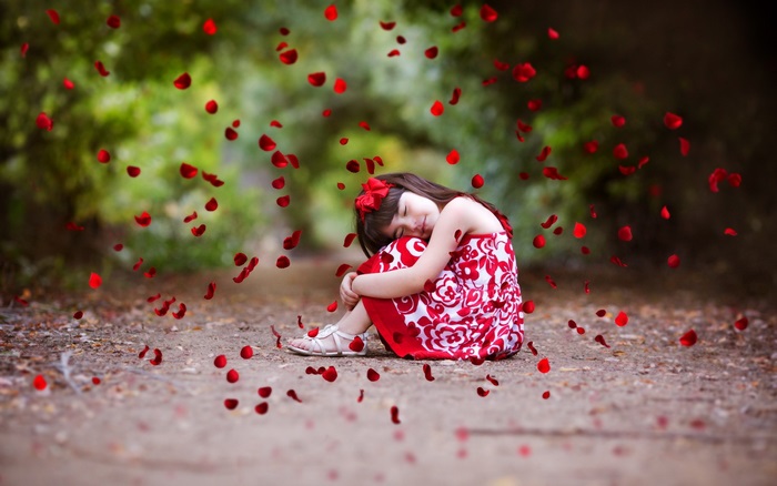Cute girl in red dress with rose petals