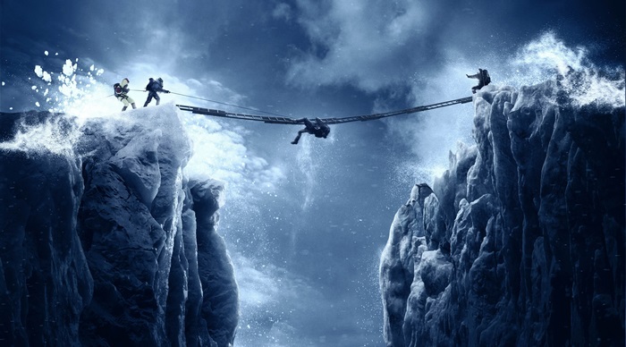 People crossing a rope bridge over icy cliffs