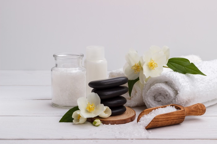Spa stones, salt, and jasmine flowers on a white table