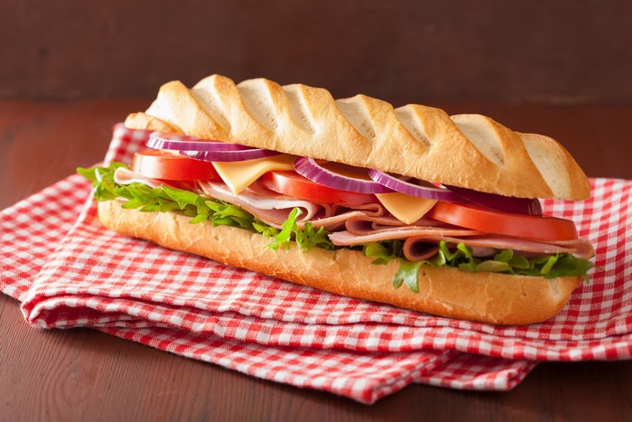 Sandwich with ham, cheese, lettuce, tomato, and onion