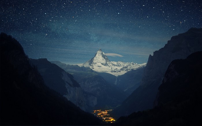 Matterhorn mountain at night with stars and village lights