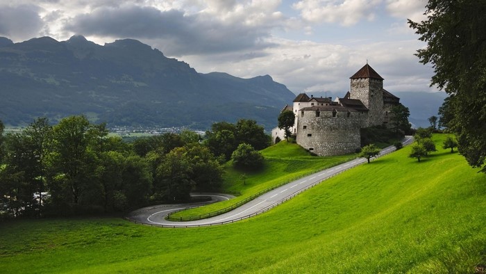 Castle on a hill with winding road and mountains
