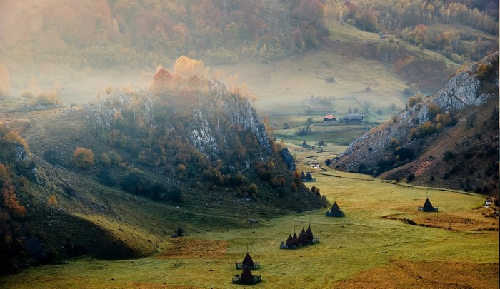 Mountain valley with haystacks and mist in Romania