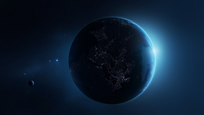 Earth at night with a bright sunrise and moon