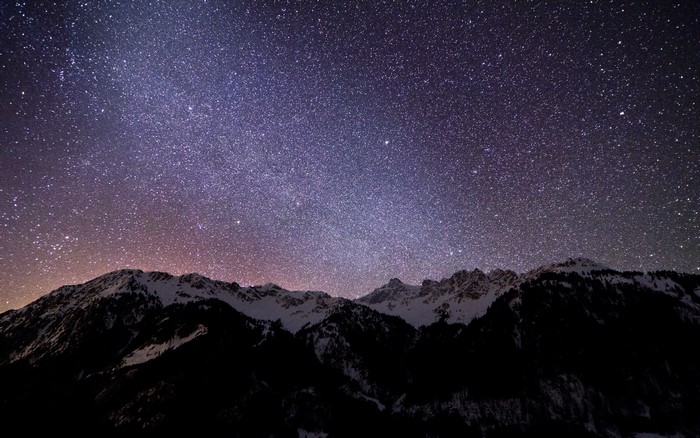 Starry night sky over snow-capped mountains