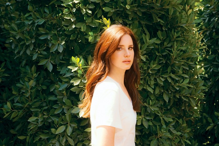 Lana Del Rey in front of green foliage