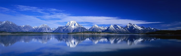 Panoramic view of snow-capped mountains reflecting in a lake