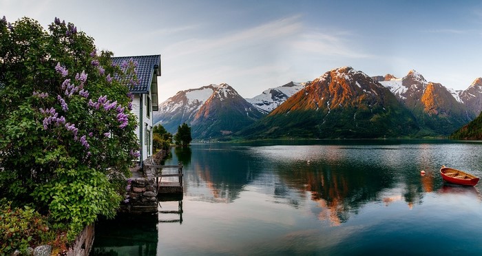 Spring sunrise over a Norwegian fjord with mountains and a house