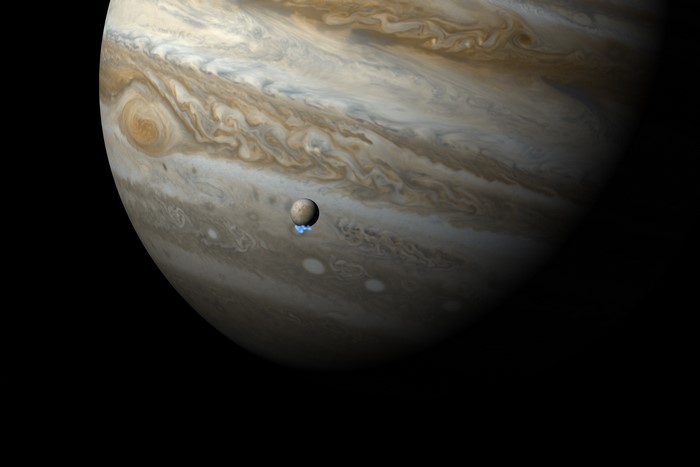 Jupiter and its moon Io with volcanic plumes