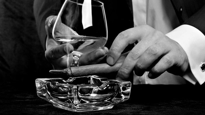 Man holding cigar and glass of alcohol