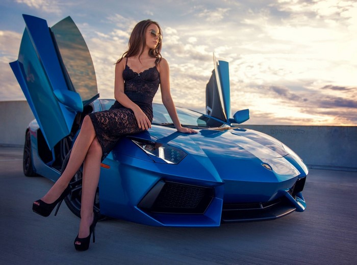 Woman in black dress sitting on a blue Lamborghini