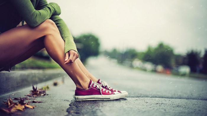 Woman in Converse sitting by the street in the rain