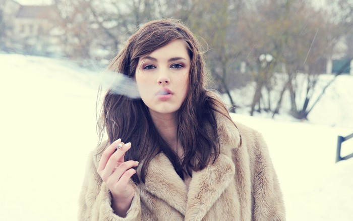 Woman in fur coat smoking in winter