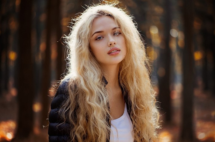 Woman with long blonde curly hair in a forest