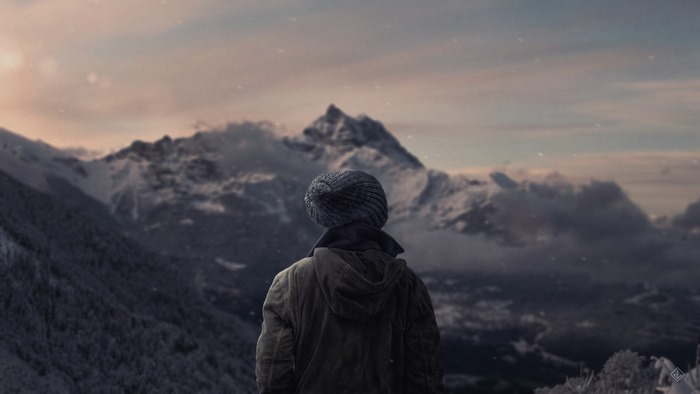 Person in beanie looking at snowy mountains