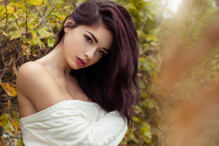 Woman with long wavy hair wearing a white sweater outdoors