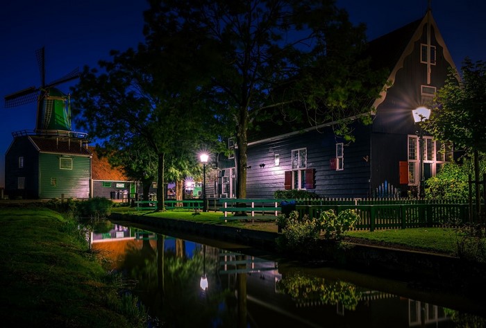 Windmill and houses by canal at night in Netherlands
