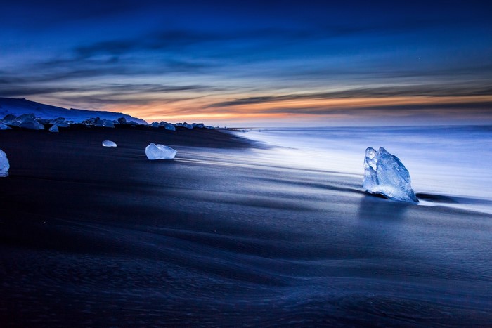 Icebergs on a black sand beach at sunset