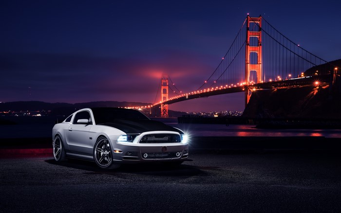 White Ford Mustang parked at night with Golden Gate Bridge